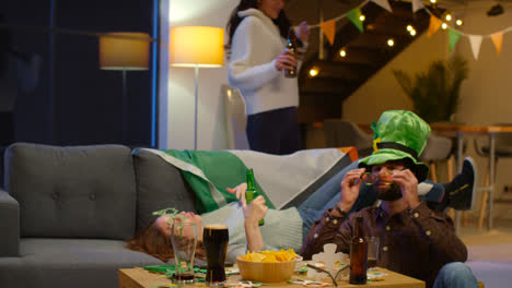 Group-Of-Friends-At-Home-Or-In-Bar-Dressing-Up-Celebrating-At-St-Patrick's-Day-Party-Drinking-Alcohol-And-Having-Fun-Dancing